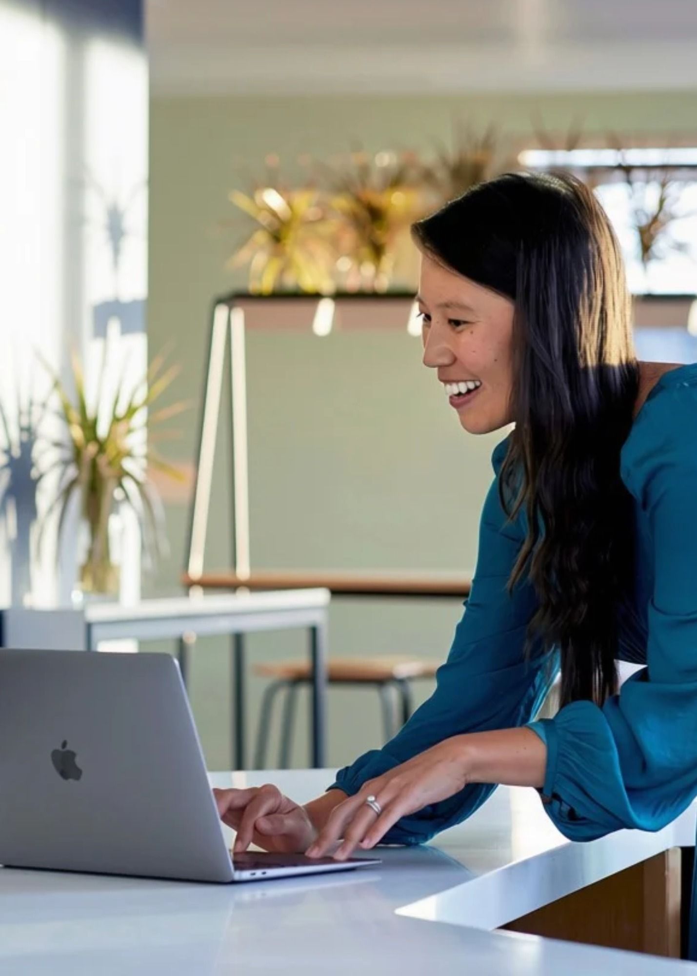 Jennie smiling as she works at a laptop in a bright office