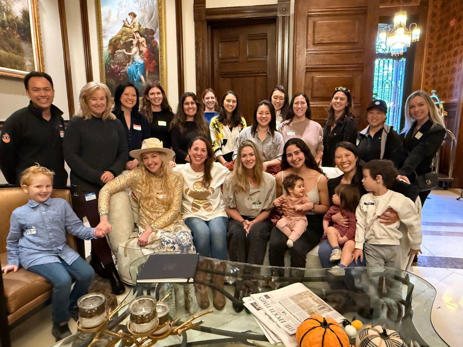 Jennie and a group of women, men and children gathered together in a historic lounge
