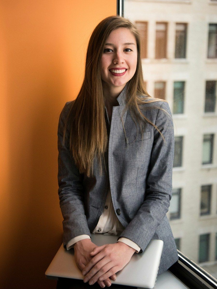 A woman founder smiling at a window, a laptop resting on her lap