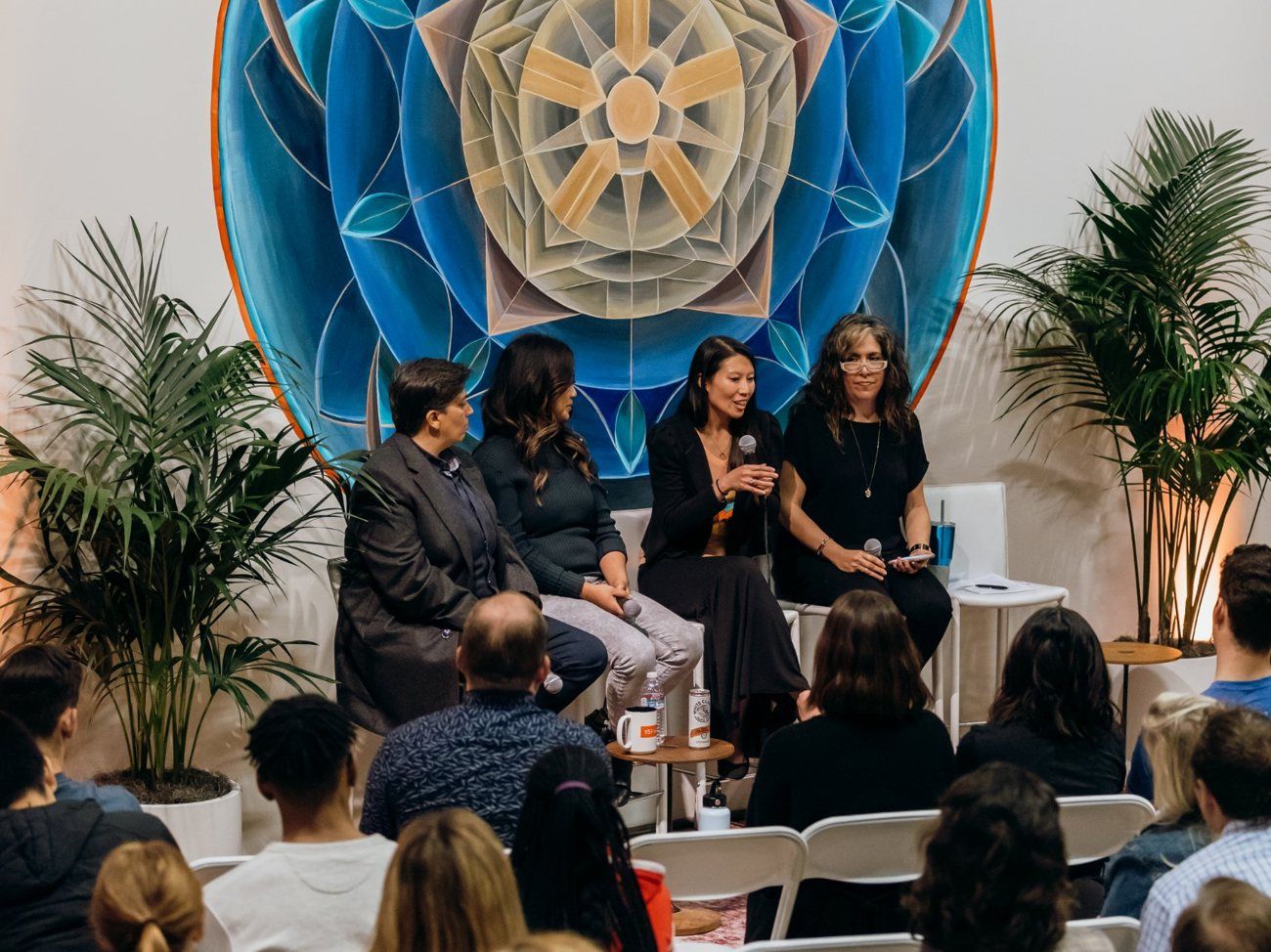 Jennie speaking on a panel in front of a mural